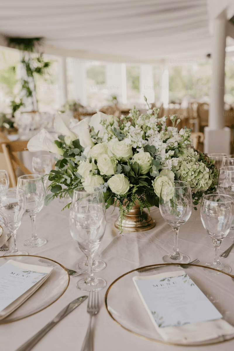 Elegant floral table centerpiece with white roses and glassware for wedding reception