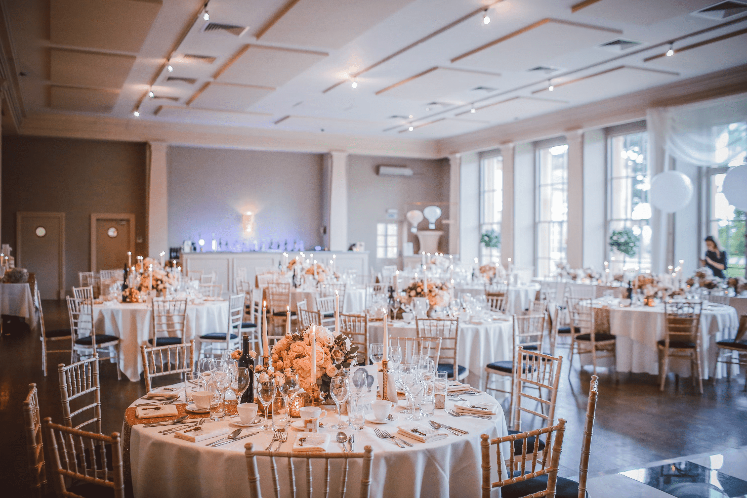 Banquet hall reception tables with candle centerpieces and formal dinner place settings