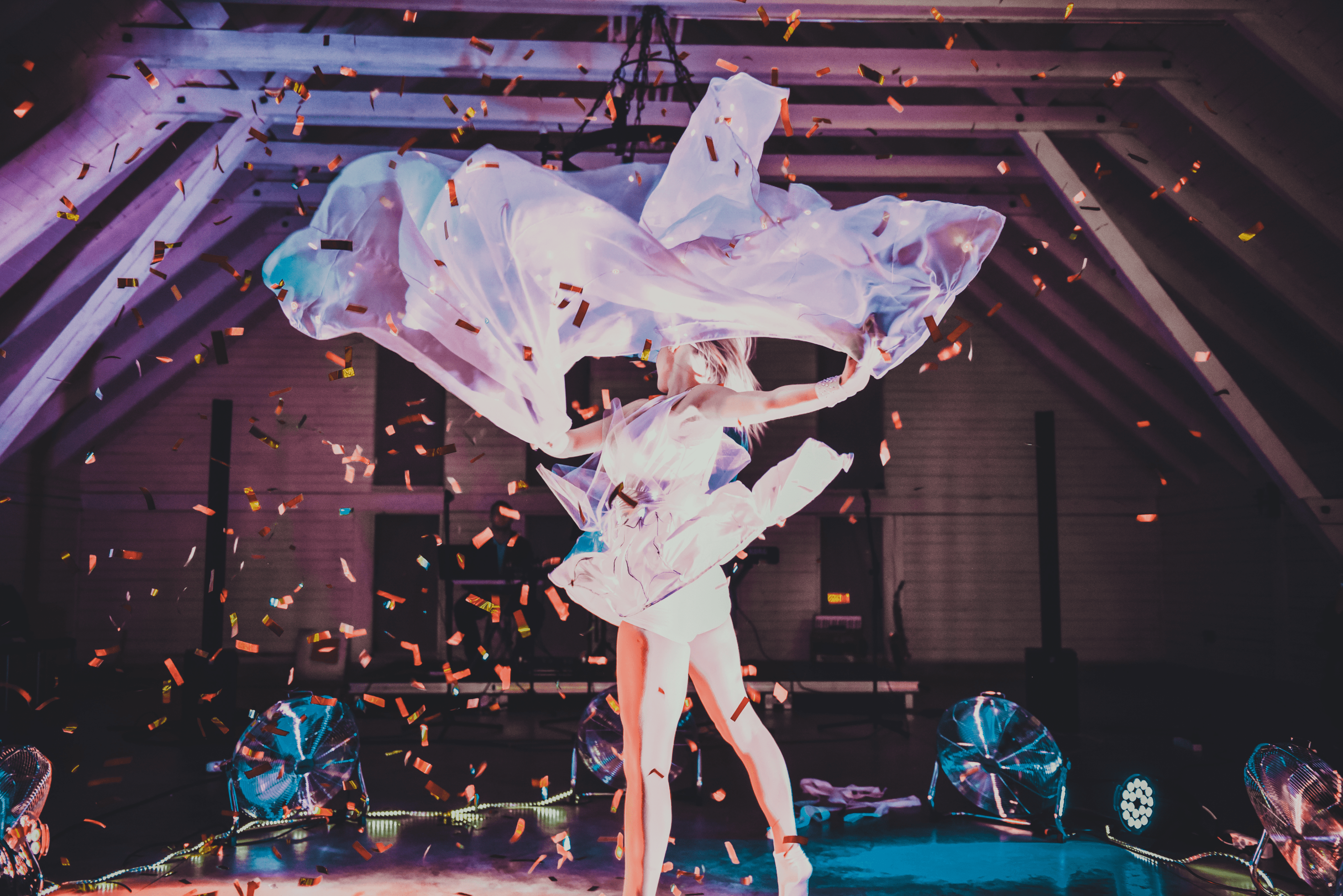Live dancer performing on stage with flowing dress, stage lighting, and confetti entertainment